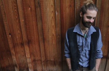 man leaning against a wood wall