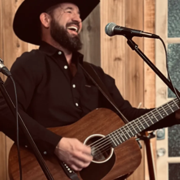 man playing guitar in cowboy hat